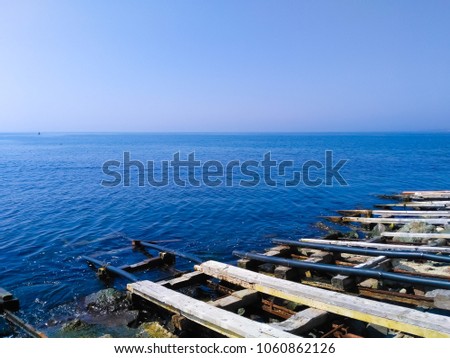 Fragment of a fishing boats parking with shore docker ramp systems on a sea background