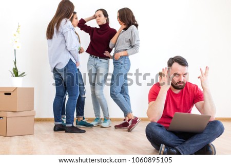 Bearded man sitting with laptop spread his hands to the sides against the background of four girls