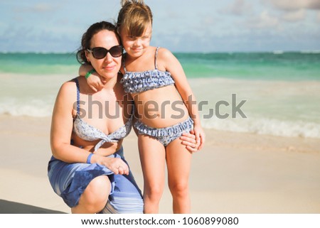 Smiling young Caucasian mother with little daughter on sandy beach