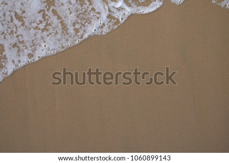top view close up detail of sea water wave motion foam on sandy beach background texture