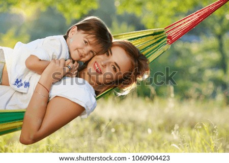 Hugging mother and daughter laying in the hammock closeup picture