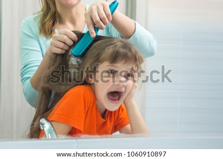 Mom and daughter are having fun while mum combing the childs hair
