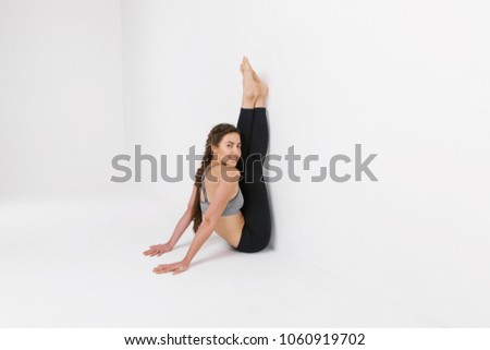 Young girl practicing yoga. Isolated on white background. Girl in yoga asana. Beautiful woman performs yoga in a white studio