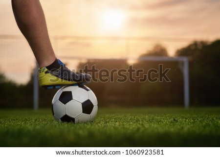 Soccer ball with player in the sunset, soccer gate in the background                               