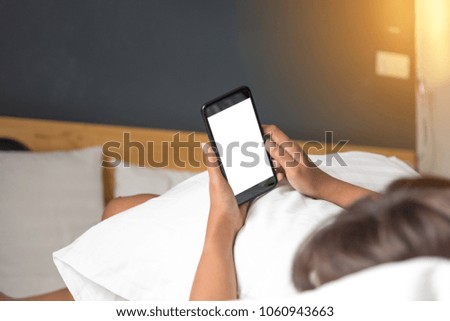 Asian Woman's hands using smartphone with blank screen in bedroom at morning.