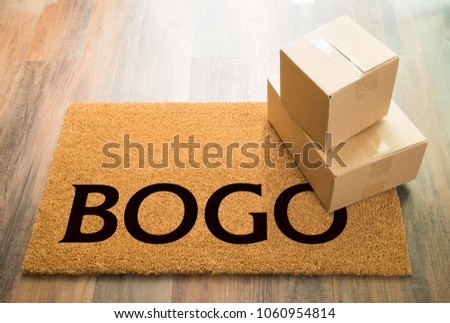 BOGO Welcome Mat On Wood Floor With Shipment of Boxes. Royalty-Free Stock Photo #1060954814