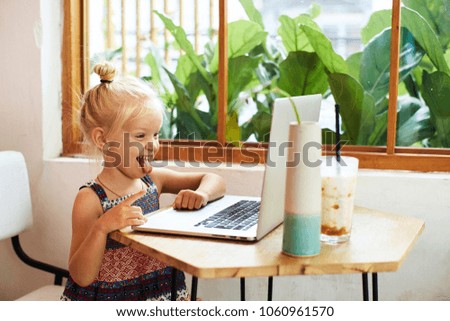 Funny little girl with her tongue out against the laptop screen