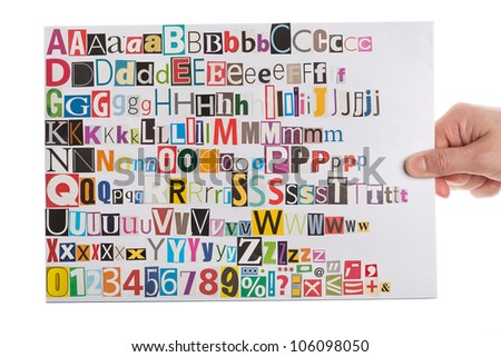 Hand holding newspaper clippings alphabet with letters, numbers and symbols, isolated on white background.