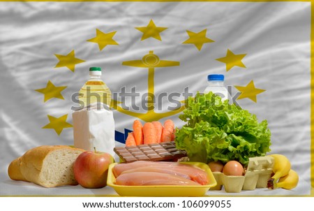 complete american state flag of rhode island covers whole frame, waved, crunched and very natural looking. In front plan are fundamental food ingredients for consumers, symbolizing consumerism