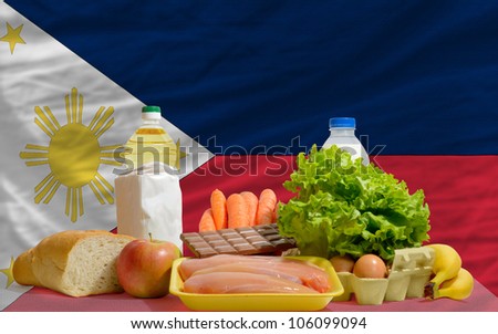 complete national flag of philippines covers whole frame, waved, crunched and very natural looking. In front plan are fundamental food ingredients for consumers, symbolizing consumerism