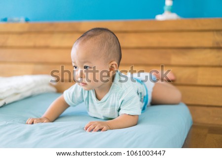 Baby boy falling down on the bed.