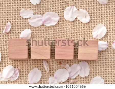 top views of four blanks blocks for copy space putting on the sack with petal of pink flower around. The concept of positive word 