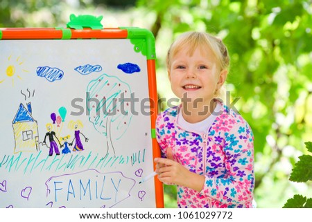 The child has drawn the drawing of family on a board in the park.
