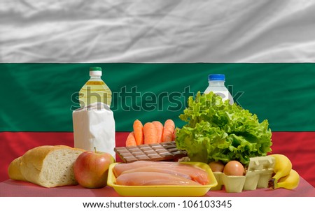 complete national flag of bulgaria covers whole frame, waved, crunched and very natural looking. In front plan are fundamental food ingredients for consumers, symbolizing consumerism an human needs