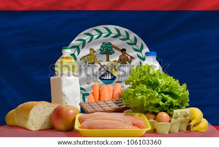 complete national flag of belize covers whole frame, waved, crunched and very natural looking. In front plan are fundamental food ingredients for consumers, symbolizing consumerism an human needs