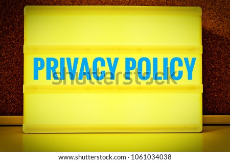 Luminous panel with the inscription in english Privacy Policy in front of a pin board, in german Datenschutzerklärung, in yellow with light blue letters