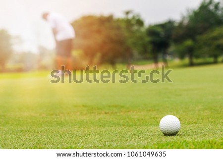 Golfer putting golf ball on the green golf with sun in morning time.