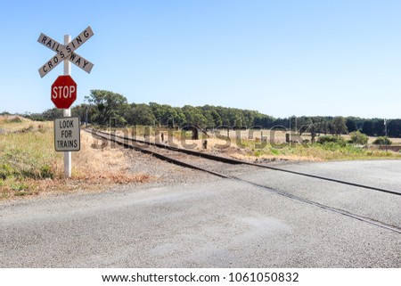 red, black and white Stop, Look For Trains, Railway Crossing warning signs at railway tracks in rural Australia