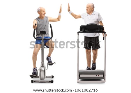 Seniors exercising on a stationary bike and a treadmill high-fiving each other isolated on white background