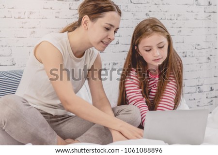 Relationship of mother and daughter concept. Mom and little girl using laptop computer to play game togethers in weekend at home.