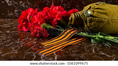 carnations, against the background of the monument, with the Gergiev ribbon and military flask