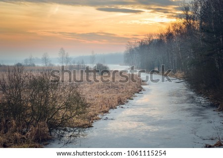 Colorful winter morning. A frozen river with a beautiful sunrise.
