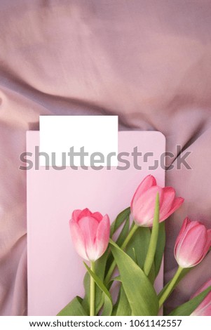 Pink tulip flowers, empty business card mockup on dust pink textile background. Copy space for text. Minimal feminine flat lay. Mock up top view