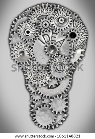 Photo of metal plate in a light bulb shape and tooth wheels with IDEA concept related words imprinted on metal surface