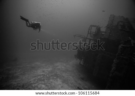 A technical diver swimming alongside of an underwater shipwreck laying on its side. The USCG Bibb is an artificial reef inside the John Pennekamp State Park in Key Largo, Florida. Royalty-Free Stock Photo #106115684