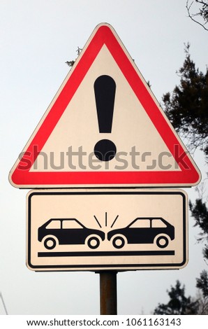 High risk of collision. A road sign with an exclamation point and two cars that crashed into each other