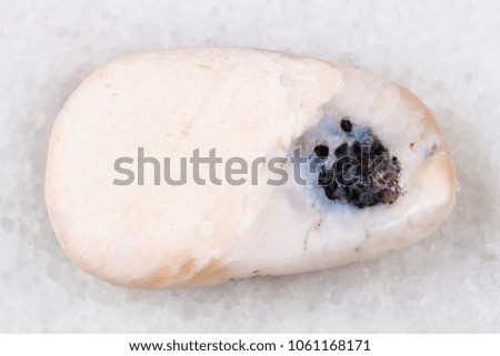 macro shooting of natural mineral rock specimen - tumbled pink opal gemstone on white marble background from Peru