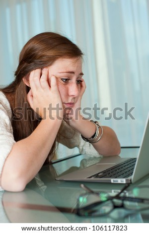 A tired young lady sitting in front of her laptop while sleeping.