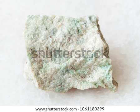 macro shooting of natural mineral rock specimen - rough Listwanite stone on white marble background