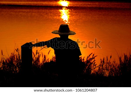 The silhouette of the fisherman waiting to fishing with beautiful sunset in Thailand.