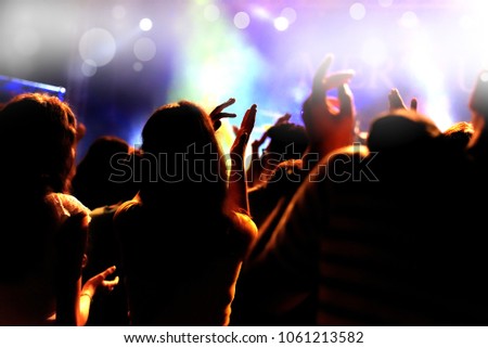 people raising arms at an open air rock music concert