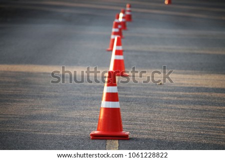Blurred bright orange traffic cones standing in a row on dark asphalt