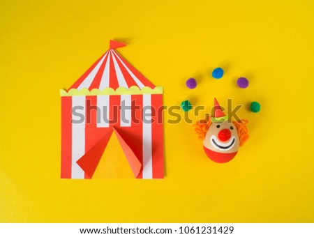 The concept of Easter with cute and cheerful handmade eggs, a clown. Circus Yellow background. Funny egg. Painted Easter eggs in different moods and facial expression 