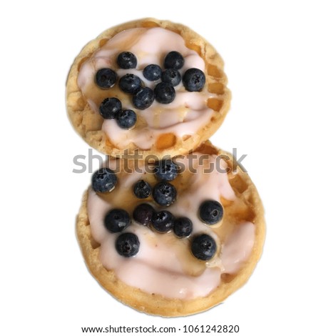 There are two waffles in the picture. They have a topping of yoghurt and honey. There are blueberries at the top. It is a white background of the picture.