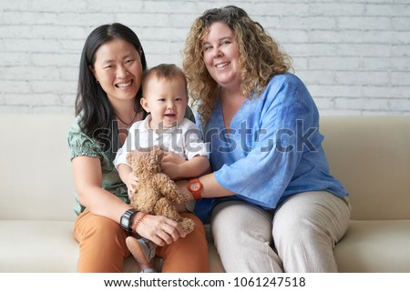 Happy multi-ethnic female couple with their adorable baby boy Royalty-Free Stock Photo #1061247518