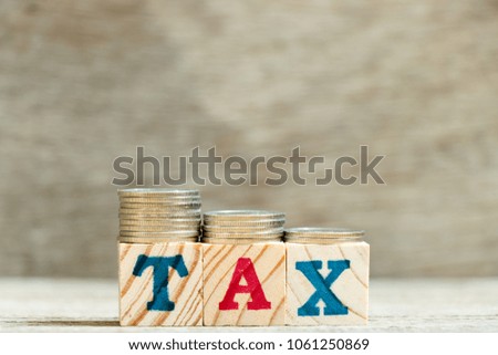 Block in word tax with coin in down trend on wood background