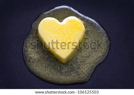 a heart shaped butter pat melting on a non-stick surface Royalty-Free Stock Photo #106125503