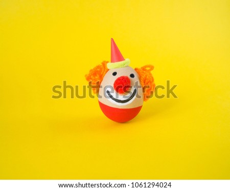 The concept of Easter with cute and cheerful handmade eggs, a clown.Circus Yellow background. Funny egg. Painted Easter eggs in different moods and facial expression 