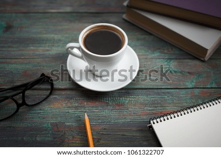 A cup of coffee in the workplace on a wooden table. A cup of coffee in the workplace on a wooden table. The concept of working outside the office