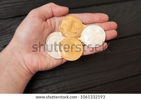 bitcoins, litecoin and ethereum in  hand on old wooden background