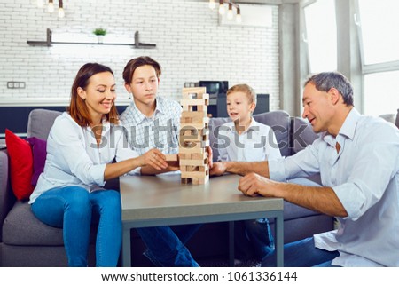 The family plays board games gaily while sitting at the table inside the room.