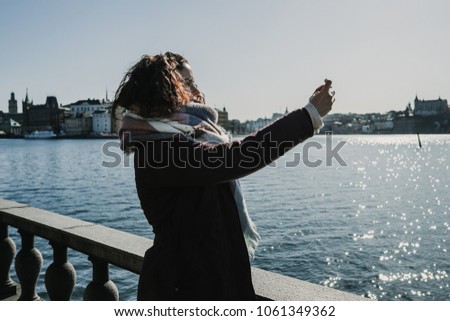 Beautiful young woman taking some pictures from her travel to Stockholm in Sweden from a beautiful view from the old city. Having fun and relaxed time. Lifestyle photography.