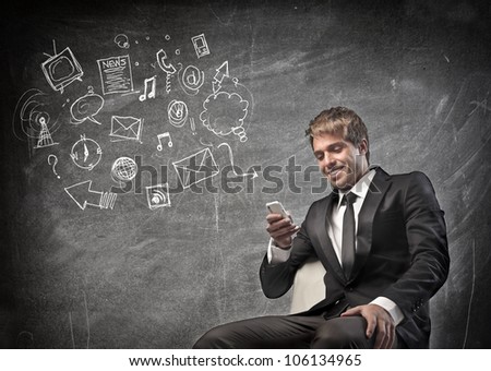 Smiling young businessman using a mobile phone with symbols beside him