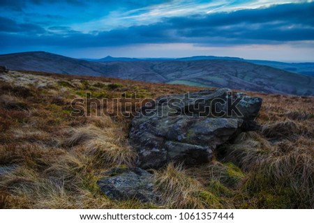 A boulder in the foreground with Shining Tor to the left and Shutlingsloe in the distance, at the Goyt Valley in The peak District. taken in evening in winter.