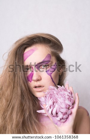 Beautiful young girl with violet  make up with violet flower in studio on gray background. Close-up portrait. Fashion, beauty, make-up, cosmetics, beauty salon concept. 