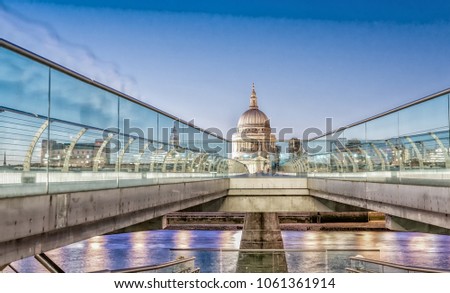 Moving people alonf Millennium Bridge in London. Night view of St Paul Cathedral.
